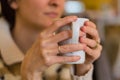 Delicate caucasian woman hands holding a white mug.