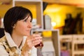 Delicate caucasian woman with short brown hair holding a glass of tea.