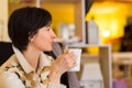 Delicate caucasian woman with short brown hair holding a white mug.