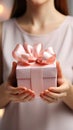 Delicate close-up: Female hands hold small gift with pink ribbon indoors.