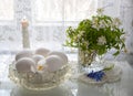Spring flowers in a glass and white eggs in a crystal vase on a white background Royalty Free Stock Photo