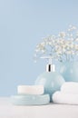 Delicate elegant ceramic decorations for bathroom - soft blue bowls, vase, white flowers, towel and soap on white wood table.