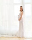 Delicate elegant pregnant woman in a white dress