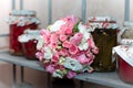 A delicate flower bouquet of white and pink roses for the bride, lying on a shelf with cans of pickles