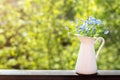 Delicate forget-me-not flowers in a white jug on a green summer background. Copy space Royalty Free Stock Photo