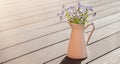 Delicate forget-me-not flowers in a white jug on a wooden background. Copy space Royalty Free Stock Photo