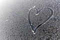 A car windshield covered with a layer of ice frost, featuring a heart or love symbol drawn on its surface. Royalty Free Stock Photo
