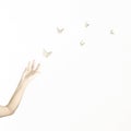 Delicate gesture of a hand that accompanies a group of origami butterflies, concept of fantasy