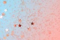 Delicate glitter star confetti on coral and blue background. Creative and moody color of the picture