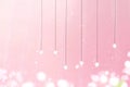 Delicate hanging stars against a soft pink backdrop in a serene setting with gentle light effects
