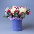 Delicate holiday bouquet in a blue velor round gift box on a blue background. Royalty Free Stock Photo