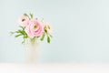 Delicate home decor with pink buttercup flowers on white wood table and mint color wall, background for design for gift, holiday.
