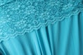 Delicate light blue guipure lace fabric on blue satin fabric