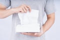 Delicate male hands pulling a white tissue paper out of a transparent crystal tissue box