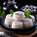 Delicate mochi desserts topped with desiccated coconut sit on a black plate, garnished with fresh mint leaves Royalty Free Stock Photo