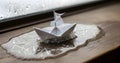 Paper Boat Sailing Through Icy Puddle on a Rainy Day Royalty Free Stock Photo