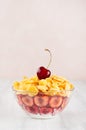 Delicate pink breakfast with golden corn flakes decorated cherry on white wood board. Royalty Free Stock Photo