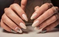 Delicate pink gel polish on long nails with a silver design. Nude manicure with a brilliant design.