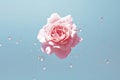A delicate pink rose floats amidst sparkling water droplets on a tranquil blue backdrop, creating a scene of serene beauty and