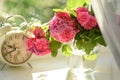 Delicate pink tea roses and a vintage alarm clock