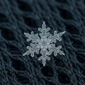 A delicate snowflake with an intricate hexagonal pattern rests on a dark woven Royalty Free Stock Photo