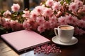 Delicate vignette, pink table hosts notebook, flowers, and coffee in charming display