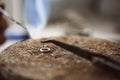 Delicate work. Close up photo of jeweler`s hands soldering a silver earring with flame from welding torch