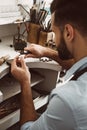 Delicate work. Close-up portrait of young male jeweler polishing silver ring at his jewelry making studio.