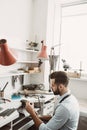 Delicate work. Side view of male jeweler making a silver ring with professional adjustable jeweler`s saw frame