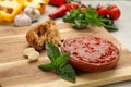 Delicious adjika sauce in glass bowl with bread and ingredients on wooden board, closeup Royalty Free Stock Photo
