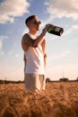 Delicious alcoholic drink in a man\'s hand. A farmer brewer carries fresh cold beer through a field of ripe wheat. Royalty Free Stock Photo