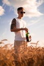 Delicious alcoholic drink in a man\'s hand. A farmer brewer carries fresh cold beer through a field of ripe wheat. Royalty Free Stock Photo