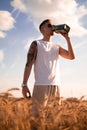 Delicious alcoholic drink in a man\'s hand. A farmer brewer carries fresh cold beer through a field of ripe wheat. Royalty Free Stock Photo