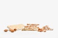 Delicious almond nougat slabs with an assortment of unpeeled almonds and almonds in their shells on a light background.