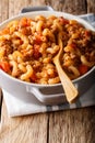 Delicious American goulash with pasta, beef and tomatoes close-up in a saucepan. vertical
