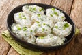 Delicious appetizer of halves of boiled potatoes with cheese yogurt sauce and herbs close-up in a bowl. horizontal