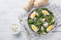 Delicious appetizer salad with radish, cucumber, lettuce mix, spinach and boiled eggs close-up in a plate. Horizontal top view