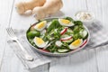 Delicious appetizer salad with radish, cucumber, lettuce mix, spinach and boiled eggs close-up in a plate. Horizontal