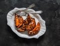 Delicious appetizer, tapas, dessert, snack - baked pumpkin with honey, cinnamon and almond petals on a dark background, top view