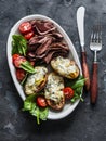 Delicious appetizer, tapas, lunch plate - beef steak, vegetables salad and baked potatoes with blue cheese on a dark background, Royalty Free Stock Photo