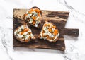 Delicious appetizer, tapas - roasted pumpkin, gorgonzola, honey, thyme bruschetta on a rustic cutting board on a light background