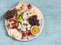 Delicious appetizer to wine - ham, cheese, grapes, crackers, figs, nuts, jam, served on a light wooden board Royalty Free Stock Photo