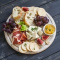 Delicious appetizer to wine - ham, cheese, grapes, crackers, figs, nuts, jam, served on a light wooden board Royalty Free Stock Photo