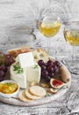 Delicious appetizer to wine - ham, cheese, grapes, crackers, figs, nuts, jam, served on a light wooden board, and two glasses with Royalty Free Stock Photo