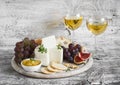 Delicious appetizer to wine - ham, cheese, grapes, crackers, figs, nuts, jam, served on a light wooden board, and two glasses with Royalty Free Stock Photo