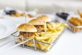 Delicious appetizers at the bar. Three burgers with french fries in a trendy metal tray, closeup.