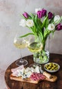 Delicious appetizers, tapas, snacks - ham, gorgonzola, camembert, salami, olives, white wine and bouquet of tulips on a wooden Royalty Free Stock Photo