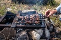 Delicious appetizing grilled meat, cooked on a fire in the courtyard of a country house. Men`s hands turn them over