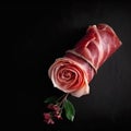 Delicious appetizing jamon rolled up in the shape of a rose on a black background, national Spanish