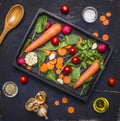 Delicious assortment of farm fresh vegetables sliced carrots, fresh spinach leaves, seasonings and butter, cherry tomatoes laid o